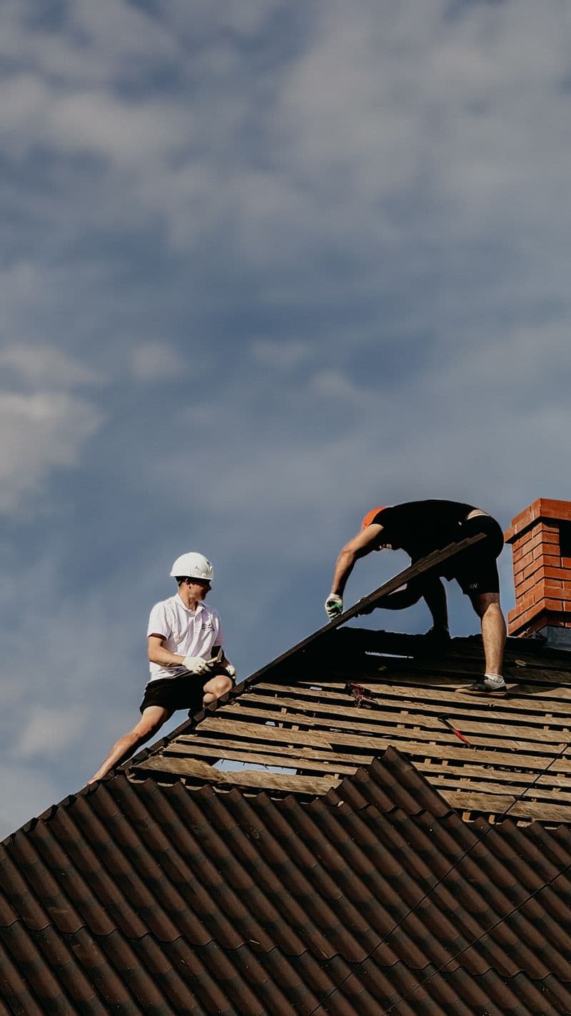 Two roofers repairing flashing near a chimney